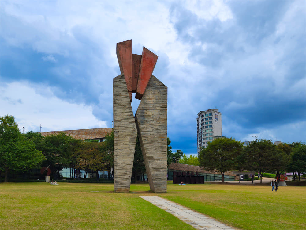 A large art sculpture placed on a vast lawn.