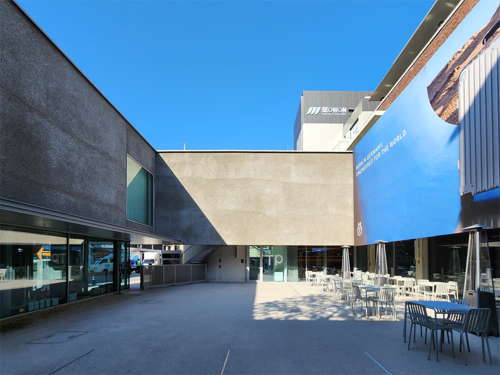 LCDC SEOUL’s courtyard is enclosed in gray concrete walls with outdoor tables and seating lining the right side